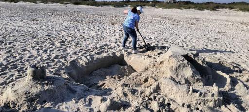 Volunteer Debbie Wasdin fills in a huge hole and flattens a sandcastle two weeks ago at Fort Clinch State Park. Sea turtle advocates say holes have become a huge issue on our beaches. Submitted