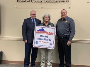 From left, Chairman John Martin; Martha Oberdorfer, deputy director of Emergency Management; and Tim Cooper, director of Emergency Management pose with National Weather Service StormReady County sign.  Submitted