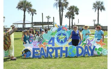The event coordinators, from left, Jackie Pagnucco, Jenn Burns, Vanessa Muzayen, Kim Galvin, Amy Beach, Vicky Strommen and Kandra Wells pose next to the Turtle Fest Earth Day sign that was donated by Card My Yard for the Earth Day Turtle Fest event held Saturday at Main Beach Park in Fernandina Beach. Photo by Ashley Chandler/News-Leader