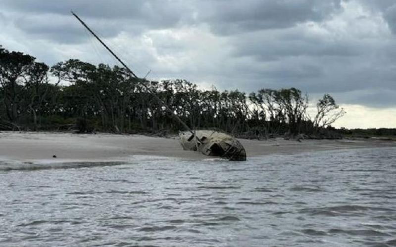 An abandoned sailboat half buried in the sand near Tiger Island will soon be removed and disposed of. Photo courtesy of Nassau County Board of County Commissioners.