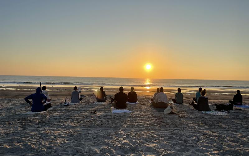 Beach yoga participants enjoying a beach sunset.