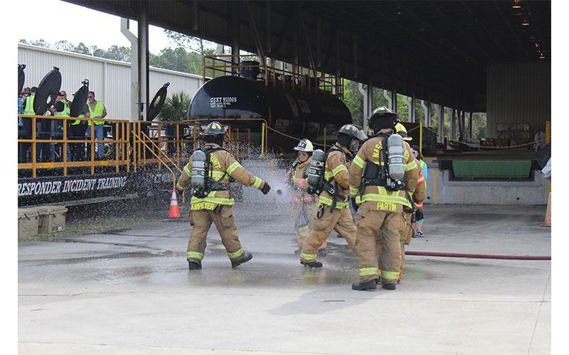 First responders are hosed down, part of the simulated railroad hazmat training to help them be prepared for an emergency involving chemicals carried by rail. Photo by Julia Roberts