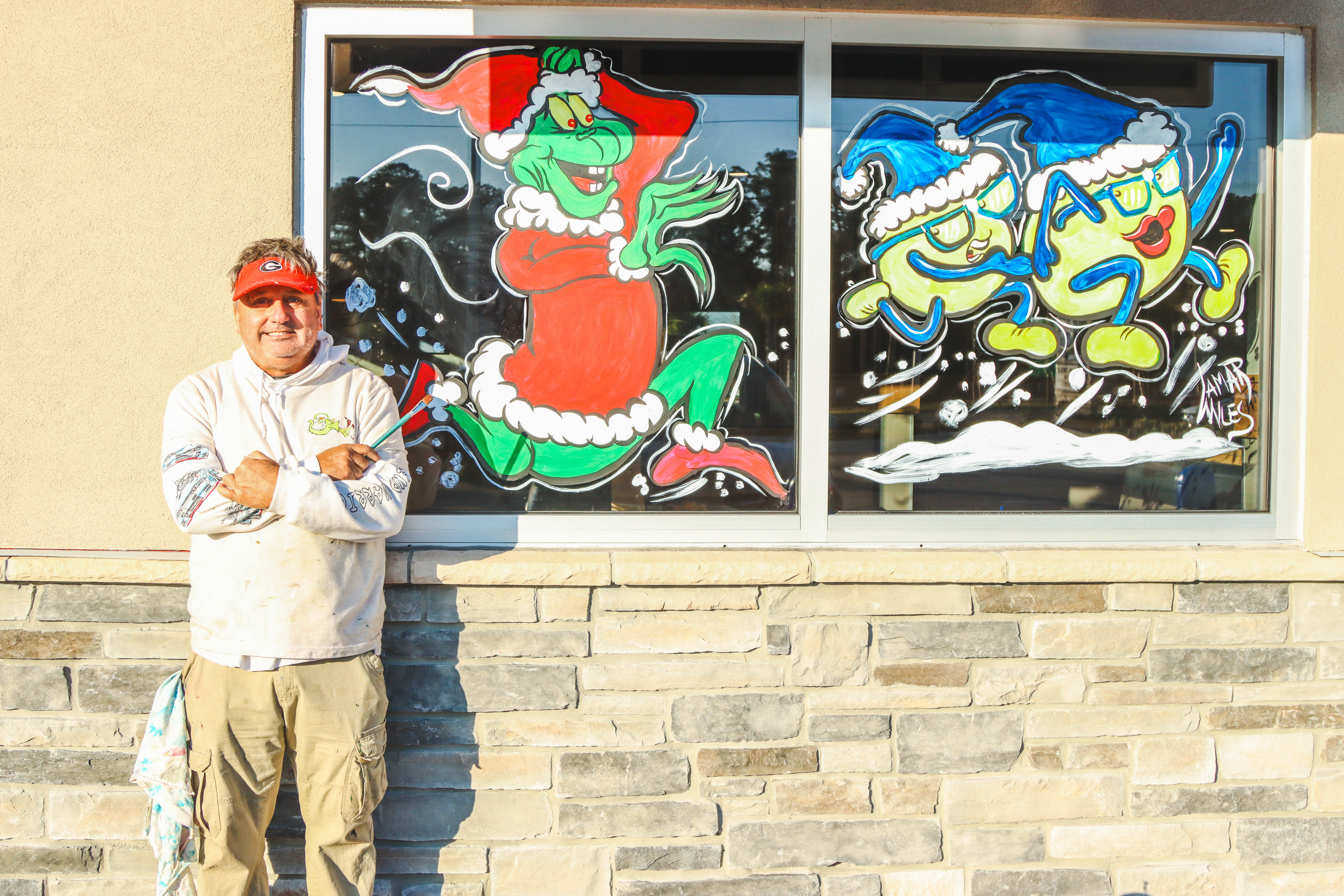 Lamar Miles of Ugly Fish Art Company poses next to some of his window-art at Culver’s in Yulee. Photo by Ashley Chandler/News-Leader