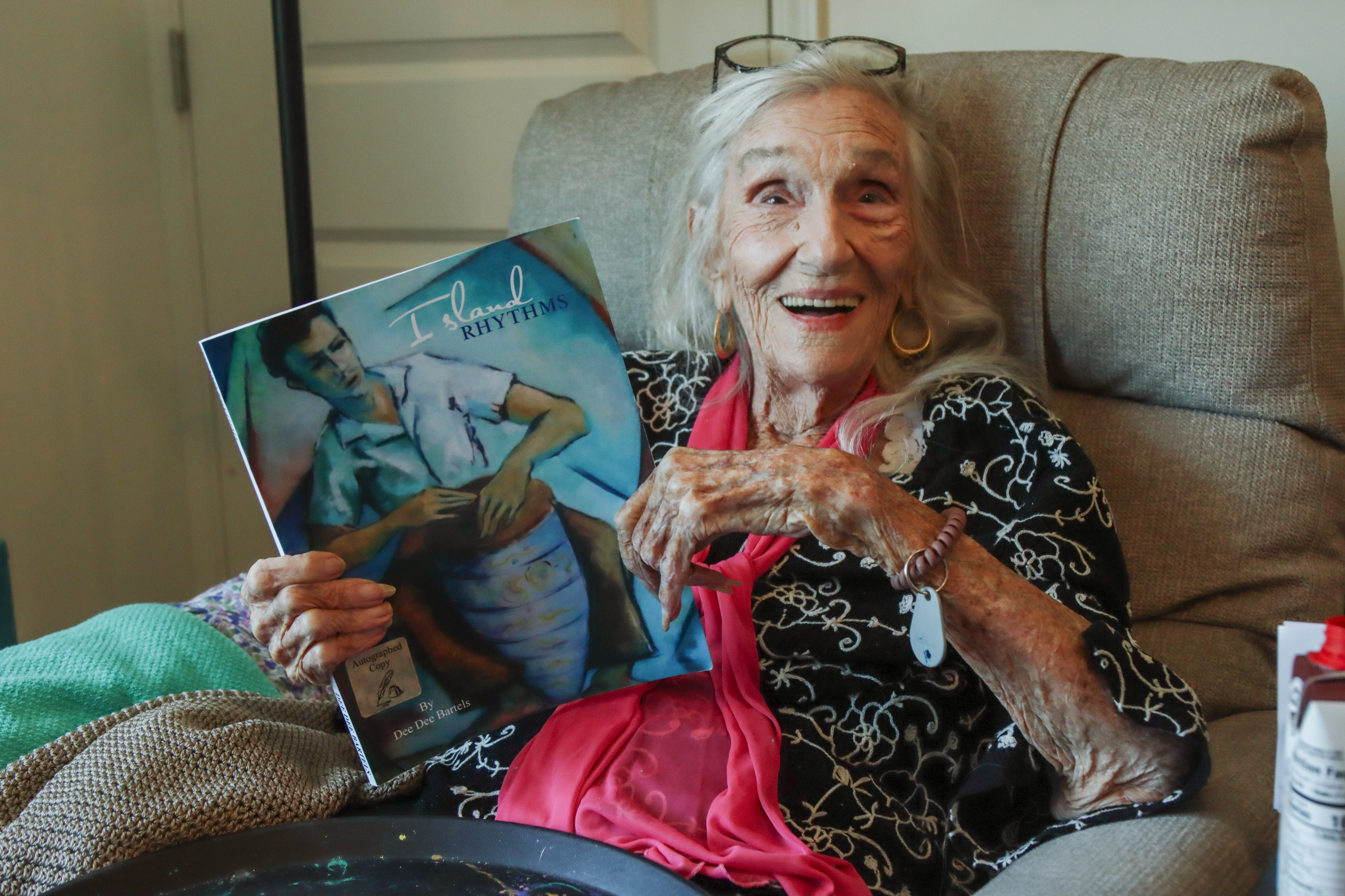 Dee Dee Bartels holds one of the books she authored during her long life in her apartment in Fernandina Beach in April 2025. Photo by Ashley Chandler/News-Leader