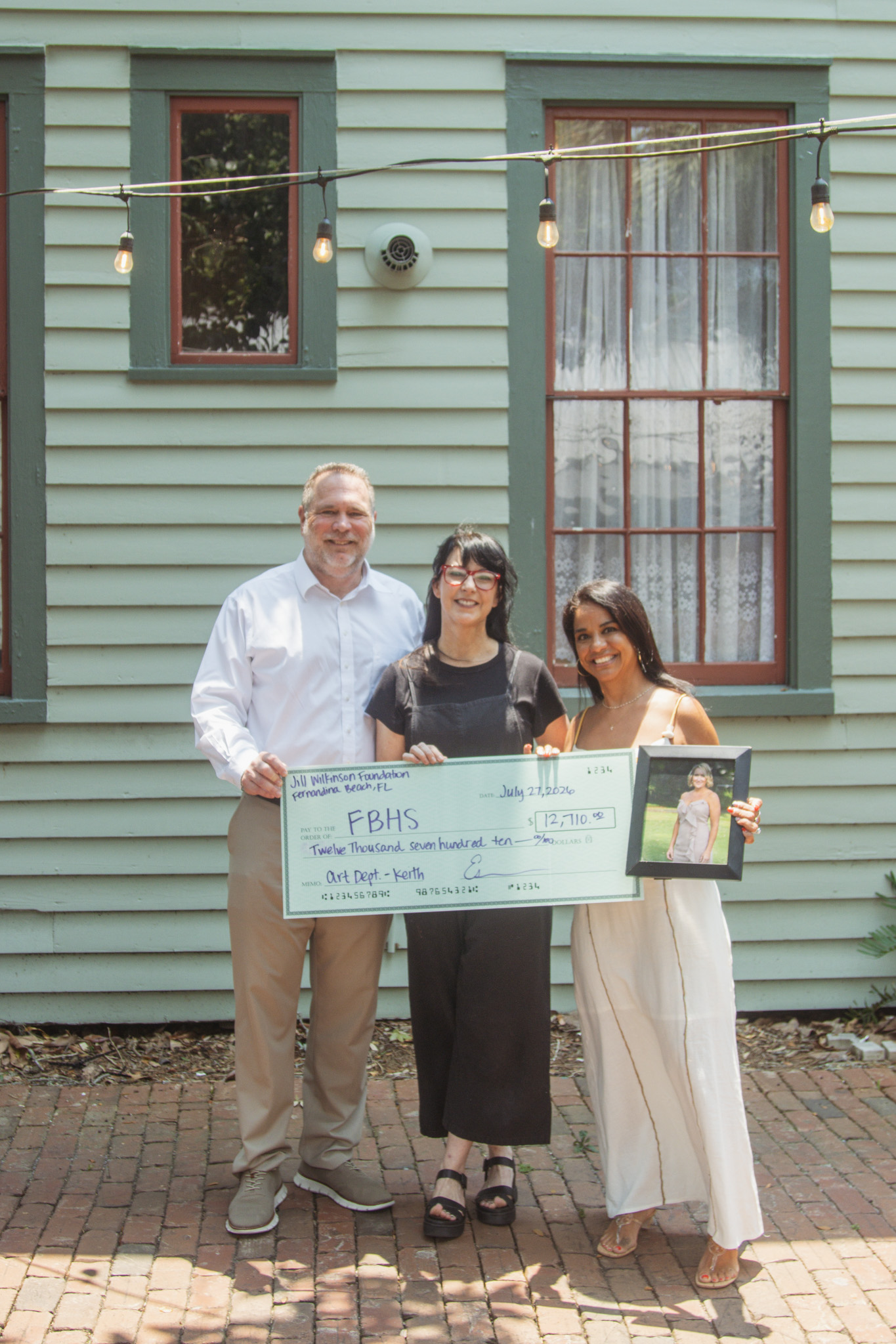 The fourth annual Fernandina Beach Art Department fundraiser and silent auction raised nearly $13,000 for the school program. From left, Todd McDonald, Joy Keith and Esmerelda McDonald pose with and a photo of their friend Jill Wilkinson and the ceremonial check presented to Keith for the Fernandina Beach Art Department. Photo by Ashley Chandler/News-Leader