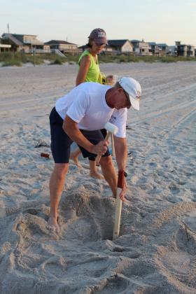 Amelia Island Sea Turtle Watch volunteer Eric Linden hammers a stake into the sand, marking the area surrounding the nest he and his wife Jan found earlier that morning.