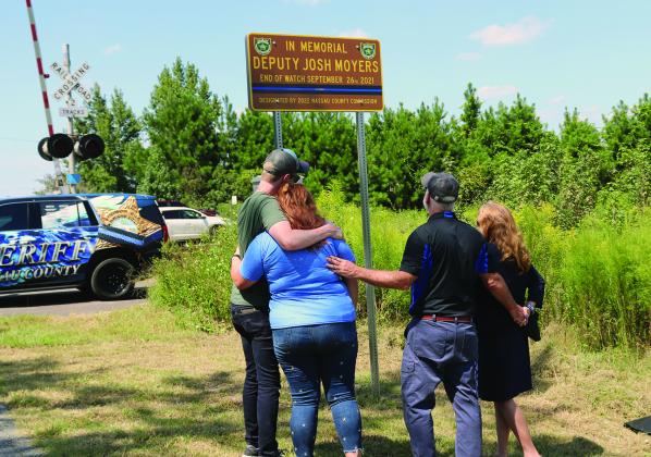 Joshua Moyers’ fiancée Ivy Carter, mom Brenda Moyers and brother Jordan Moyers look at the sign with Tim. Photo by Kathie Sciullo/Nassau County Record.