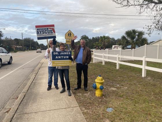 Election supporters wave at voters as they turn into Lighthouse Bible Baptist Church..