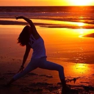 Deb Cunningham in an inverted warrior pose at sunset.
