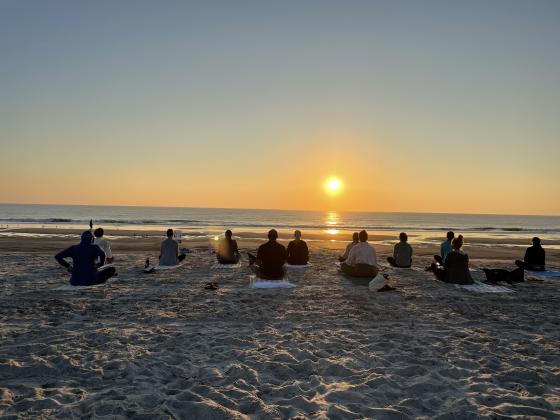 Beach yoga participants enjoying a beach sunset.