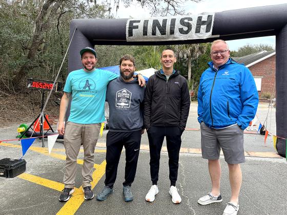 Florida Roots Trail Series foot race directors, from left, Daniel Larkin, Alex Johnston and Matt Mueller with Mike Brooks of First Port City Bank, which sponsored the winner’s awards,