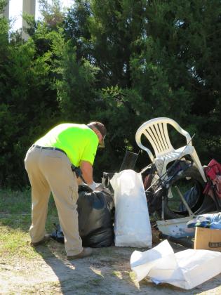 Volunteers clean up litter under the Shave Bridge, where drivers without their loads tied down often lose them over the railing. Photo by Holly Dorman/News-Leader