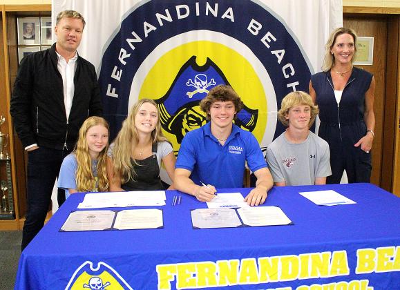 Jamieson Keith, Brooks Rohe and Andre Lucas signed national letters of intent to play their respective sport in college. Keith is a baseball player at Fernandina Beach High School, and Rohe and Lucas played football for the Pirates. They are pictured April 27 with friends, family and coaches at the spring signing day in the media center. Photo by Beth Jones/News-Leader