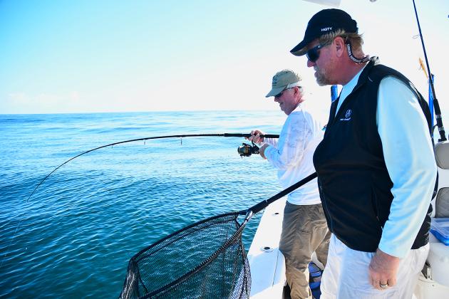 Greg Cook puts a deep bend in his fishing rod, hoping to catch a sizable win-ter cobia, as fellow angler Bill Fassbender waits patiently with his landing net. Submitted photo