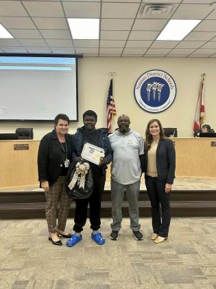 From left, Superintendent of Nassau County School District Kathy Burns, Ryan Peterson, Ryan’s grandfather, Coach Pete, and Anna Crawford, Fernandina Beach Middle School principal, stand with Peterson to share his accomplishments during a recent school board meeting.  Submitted