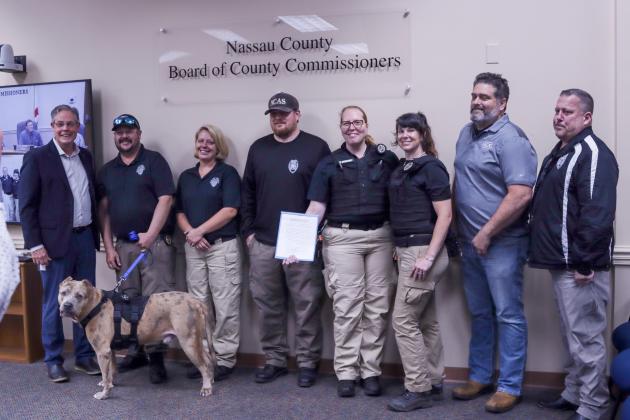 The Nassau County Board of County Commissioners proclaimed next week, April 14-20, as Animal Care &amp; Control Appreciation Week in the county. Pictured are, from left, Vice Chairman A.M. “Hupp” Huppman and NCAC staff members M. Pruitt, C. Raulerson, L. Eckardt, W. Eberhardt, N. Laferriere, C. Thorton. T. Maguire and, at the bottom, Ted E. Bear, the dog. Photo by Ashley Chandler