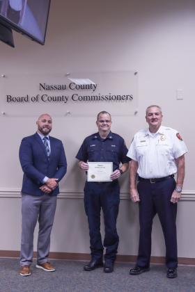 County Manager Taco Pope poses with Greg Jones, who was recognized for 30 years with Nassau County Fire Rescue, and Fire Chief Brady Rigdon at the Nassau County Board of County Commissioners meeting Wednesday morning. Photo by Ashley Chandler/News-Leader