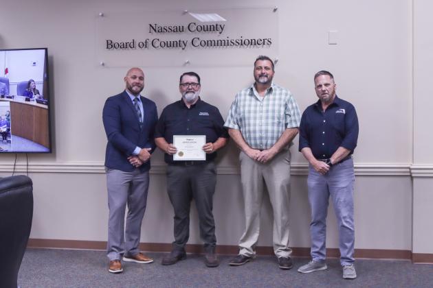 County Manager Taco Pope poses with Darren Marsh, who was recognized for 25 years working for the Road and Bridge Department, Road Department Assistant Director David Hearn and Public Works Director Doug Podiak at the Nassau County Board of County Commissioners meeting Wednesday morning. Photo by Ashley Chandler/News-Leader