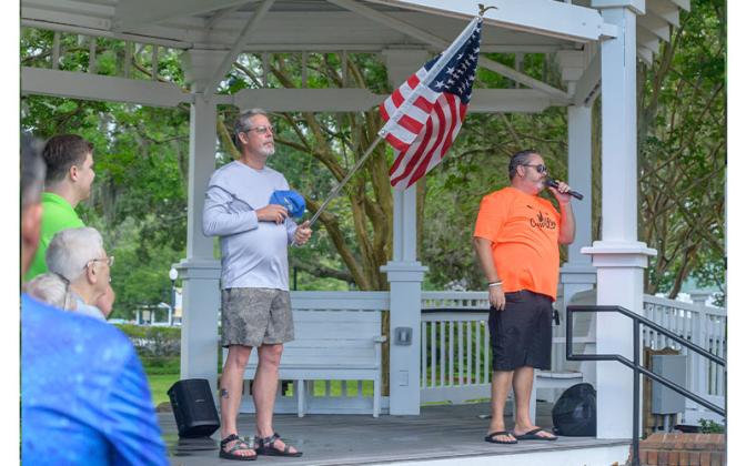 Kevan Wilson sings the National Anthem to kick off the Cross the Line Paddle for Veterans event Saturday while Nassau County Commissioner A.M. “Hupp” Huppman holds the flag. Photos by Mariah Lovin/The Barefoot Photographer