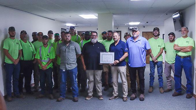 Darren Marsh of the Road and Bridge Department, center left, and Public Works Director Doug Podiak, center right, stand with county workers who have taken part in the the Nassau County Equipment Operator Apprenticeship Program. Marsh and Podiak hold the 2024 Achievement Award from the National Association of Counties given to the program. Photo by Ashley Chandler/News-Leader