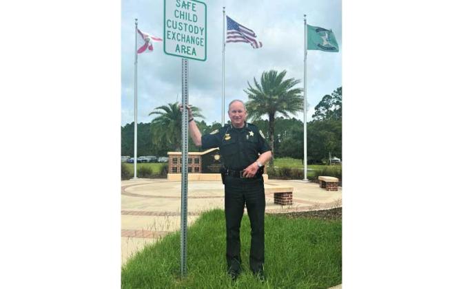 Sheriff Bill Leeper stands beside a sign that designates a secure, neutral location for parents sharing custody to safely transfer their children. Submitted photo