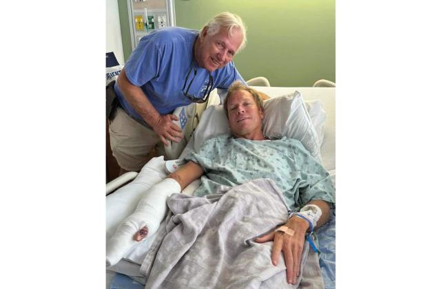 Terry Lacoss, left, visiting with Benny Hendrix in the hospital not long after Hendrix underwent surgery to repair his arm after a shark bite. Submitted