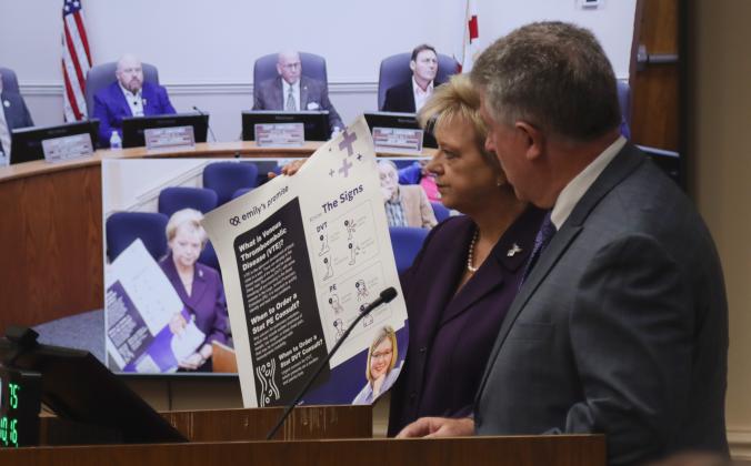 Janet Adkins, Nassau County Supervisor of Elections, holds up a sign that is part of a poster campaign started by Emily's Promise, the nonprofit Adkins and her husband, Doug, right, started in their daughter's name. Emily Adkins died in October 2022 of a massive Massive Pulmonary Embolism. Photo by Ashley Chandler/News-Leader