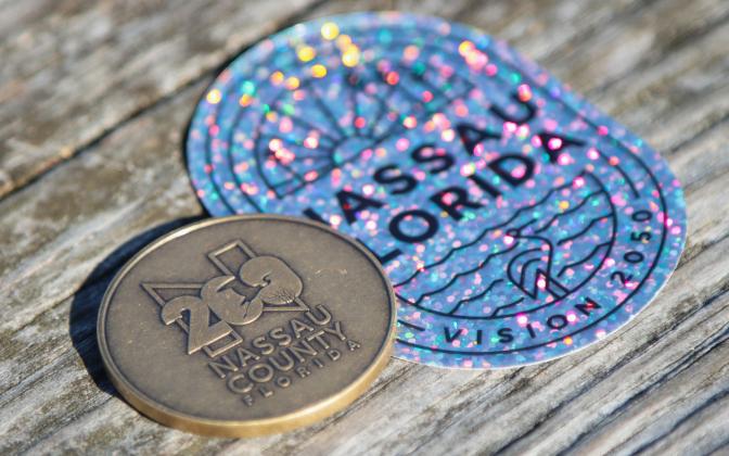 A Nassau County Bicentennial Challenge Coin and a Vision 2050 sticker. Photo by Ashley Chandler/News-Leader