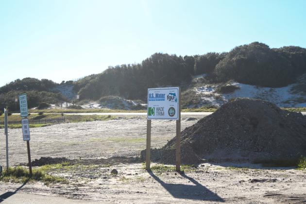 A sign in near the NaNa Dune in American Beach displays the logos of the organizations involved in the American Beach Water and Sewer Project: General Contractor, U.S. Water Service Corporation; Project Manager, Florida Governmental Utility Authority; Engineer of record, Wade Trim; and Project Owner, Nassau County, Florida. Photo by Ashley Chandler/News-Leader