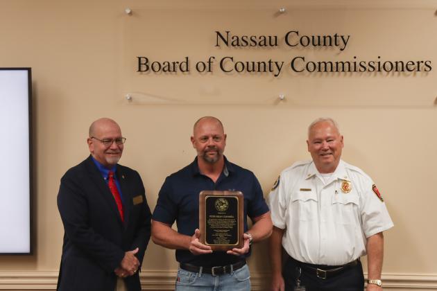 John Martin, Peter Gunnel, and Chief Greg Roland pose for a photo Dec. 18 with a plaque recognizing Gunnel's retirement after 31 years with Fire Rescue.