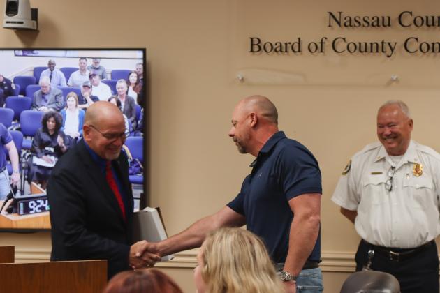 John Martin, left, shakes hands with Peter Gunnell, retiring after 31 years with Fire Rescue. Photo by Ashley Chandler/News-Leader