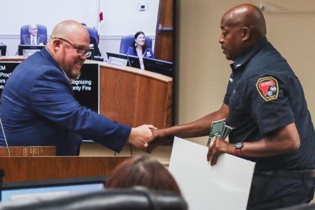 Dale Green shakes hands with Commissioner Klynt Farmer before the Board of County Commissioners recognized Green's retirement in October. Photo by Ashley Chandler/News-Leader