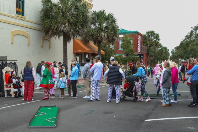 Families, many dressed in holiday-themed pajamas, wait in line for their photo opportunity with Santa at the Black Friday Pajama Party in Downtown Fernandina Beach. Photo by Ashley Chandler/News-Leader