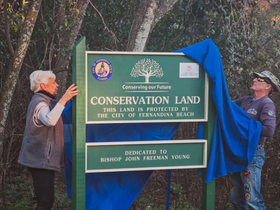 Fernandina Beach Conservation and Environmental Manager Kathy Russell and Jack Imber remove the cover from the Conservation Land sign, dedicating the city’s land on North 11th Street to Bishop John Freeman Young. Photos by Ashley Chandler/News-Leader