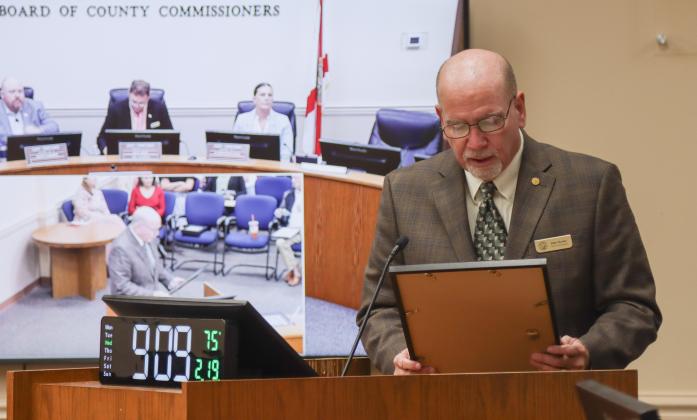 Commissioner John Martin reads a proclamation into the record recognizing the retirement of David Crout from the Road Department in January at the Feb. 19 Board of County Commissioners meeting. Photo by Ashley Chandler/News-Leader