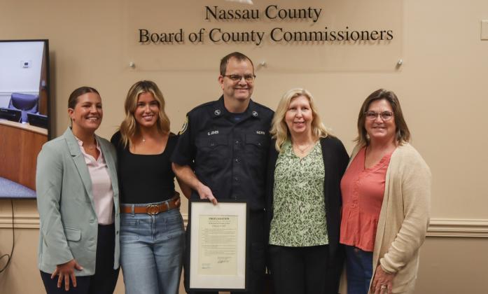 Gregory Jones, middle, is pictured with his family and Commissioner Alyson McCullough, left, after the county recognized his retirement from Nassau County Fire Rescue at the Feb. 19 Board of County Commissioners meeting. Photo by Ashley Chandler/News-Leader