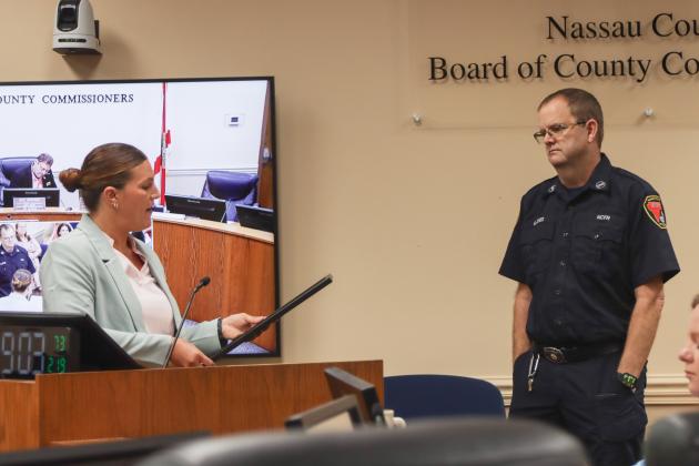 Commissioner Alyson McCullough, left, presents a proclamation to Gregory Jones recognizing his retirement from Nassau County Fire Rescue at the Feb. 19 Board of County Commissioners meeting. Photo by Ashley Chandler/News-Leader
