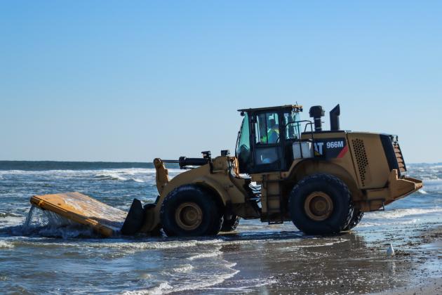 Workers clean dredging equipment Monday at Main Beach. Photo by Ashley Chandler/News-Leader
