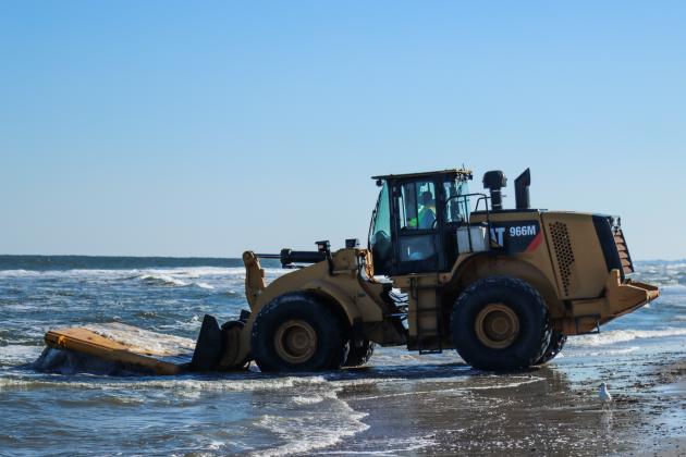 Workers clean dredging equipment Monday at Main Beach. Photo by Ashley Chandler/News-Leader