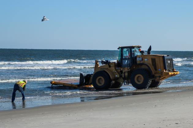 Workers clean dredging equipment Monday at Main Beach. Photo by Ashley Chandler/News-Leader