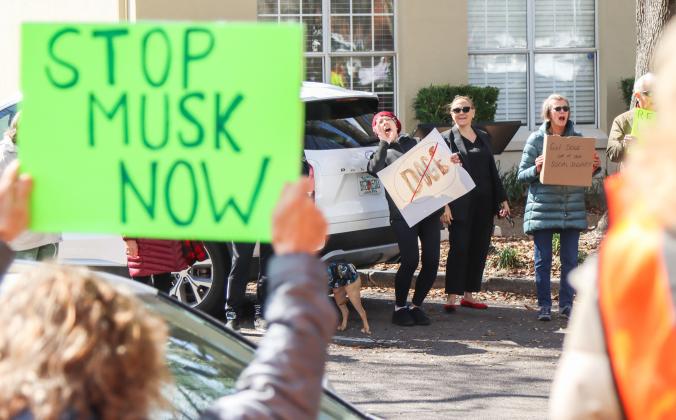 Helen Santiago, middle left holding the DOGE sign, chants at a rally on Thursday in Downtown Fernandina Beach. Beside her is Nassau County Democratic Party Chair Suzanne Sapp. Protesters were outside of Congressman Aaron Bean's Fernandina Beach office to voice their opinion on DOGE, Social Security and Elon Musk to Bean and his staff. Photo by Ashley Chandler/News-Leader