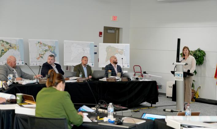 Director of Strategic Advancement and Economic Resources Brandy Carvalho speaks at the podium during the two-day Winter Strategic Planning Session held March 13 and 14 at Florida State College at Jacksonville, Betty P. Cook Center, in the Nassau Room. From left, Commissioner Klynt Farmer, Deputy County Manager Robert Companion, Assistant County Manager Marshall Eyerman, County Manager Taco Pope and Carvalho. Photo courtesy of Nassau County