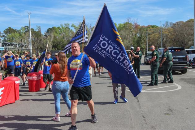 Sgt. Bill Quick waves the Special Olympic Torch Run Flag on Friday in front of Hagan's Ace Hardware following the 1.26-mile run. Photo by Ashley Chandler/News-Leader