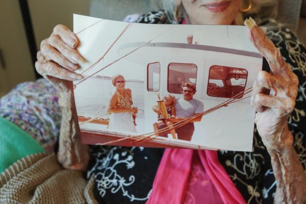 Dee Dee Bartels holds up a photo of her, left, and her co-captain and his son, during a shrimp boat race years ago, where their boat took second place. Photo by Ashley Chandler/News-Leader