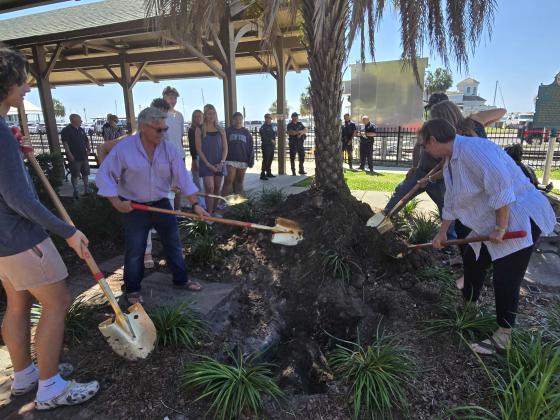 Fernandina Beach City Commissioners Tim Poynter and Genece Minshew, Communications Manager Mary Hamburg and Youth Advisory Committee Vice Chair Clay Hicks throw dirt to bury a time capsule that will be opened in 2075. Photo by Julia Roberts/News-Leader