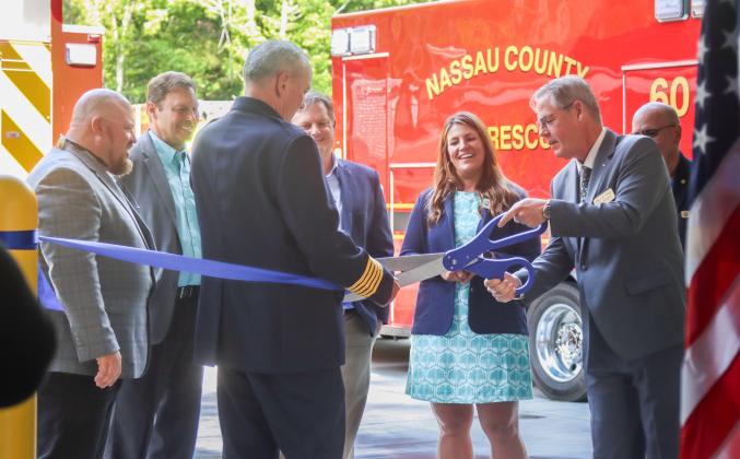 Fire Chief Brady Rigdon hold the cermonial ribbon as Commissioner A.M. "Hupp" Huppmann cuts little pieces off after the ceremonial ribbon cutting held Wednesday for Fire Station 10 in Yulee. From left, commissioners Klynt Farmer, Jeff Gray, President of GreenPointe Mike Taylor and commissioners Alyson McCullough and John Martin watch. Photo by Ashley Chandler/News-Leader