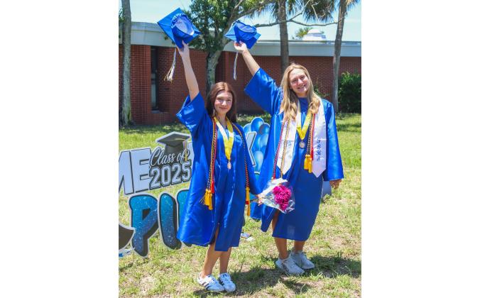 Salutatorian Brittany Cochran and Valedictorian Ivy Bradley hold their caps up high Thursday at Southside Elementary. The Fernandina Beach High School graduates traveled to all the Elementary Schools in Fernandina Beach on Thursday to walk around the halls they came from. Photo by Ashley Chandler/News-Leader