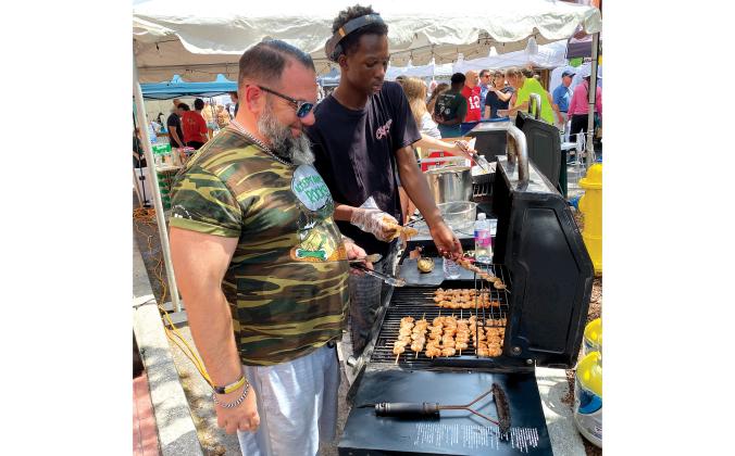 Yulee High School wrestling coach Brandon Crowder and Dieuseal Dauphin grill up shrimp skewers Saturday for the Hornets’ booth at the 60th annual Isle of Eight Flags Shrimp Festival. Photo by Beth Jones/News-Leader