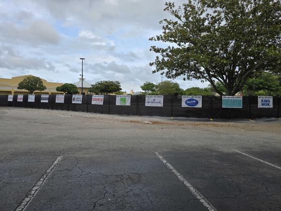 The blacked-out fencing closing off the public from the construction areas, holds signs informing visitors of the nearby business that are still open for business. Photo by Julia Roberts/News-Leader