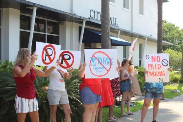 Residents hold signs outside Fernandina Beach City Hall in opposition to paid parking. (SAGE BOAZ/News-Leader)